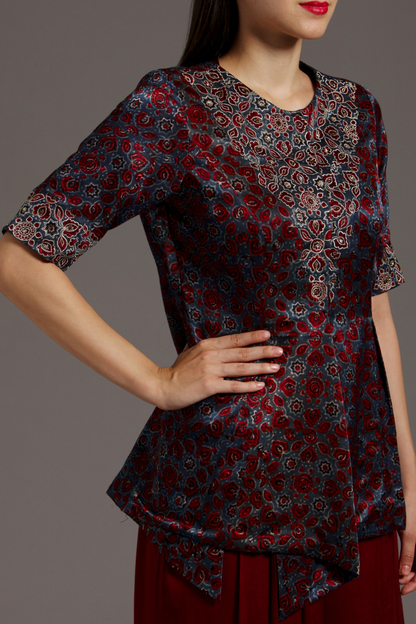 "Stunning Maroon Peplum Top in Pure Ajrakh Modal Silk with Intricate Embroidery on Yoke and Sleeves, Paired up with Maroon Pleated Pants in Crepe."
