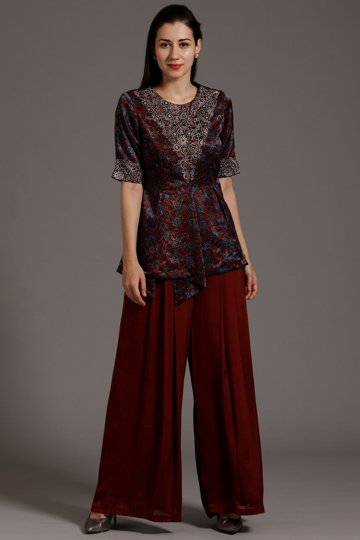 "Stunning Maroon Peplum Top in Pure Ajrakh Modal Silk with Intricate Embroidery on Yoke and Sleeves, Paired up with Maroon Pleated Pants in Crepe."