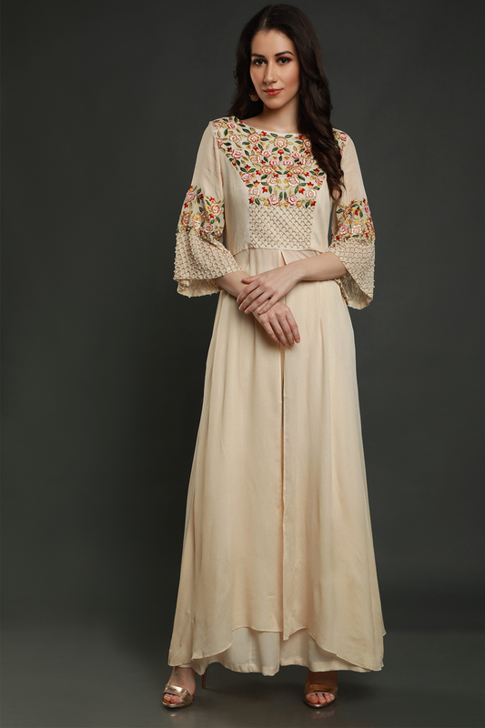 Elevate your style with a cream tunic, intricately embroidered with resham thread, pearls, and cutdana work. Paired with stylish sharara pants.