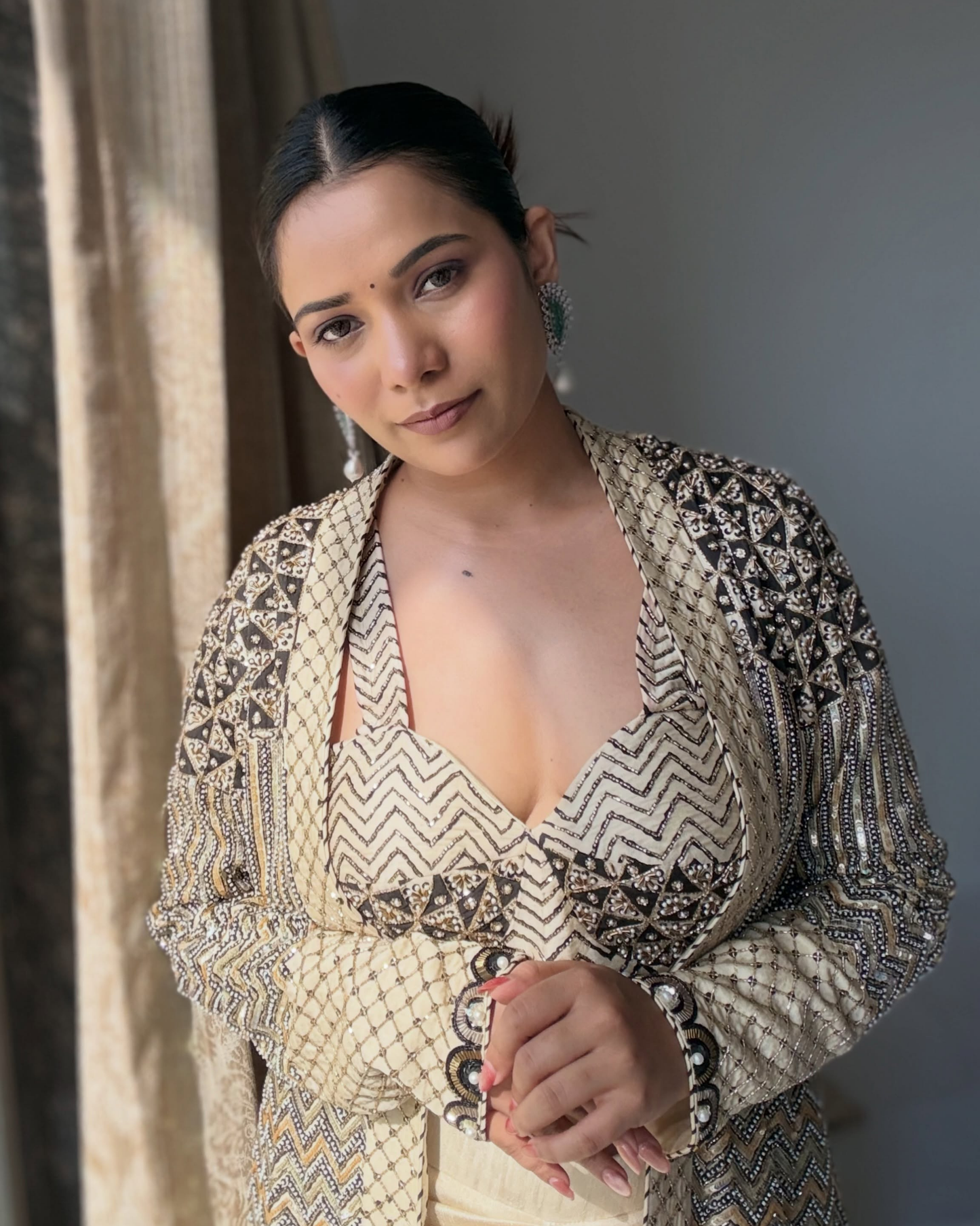 A Richa Archana wearing a heavily embellished beige and black traditional outfit with intricate silver beadwork and matching statement earrings.