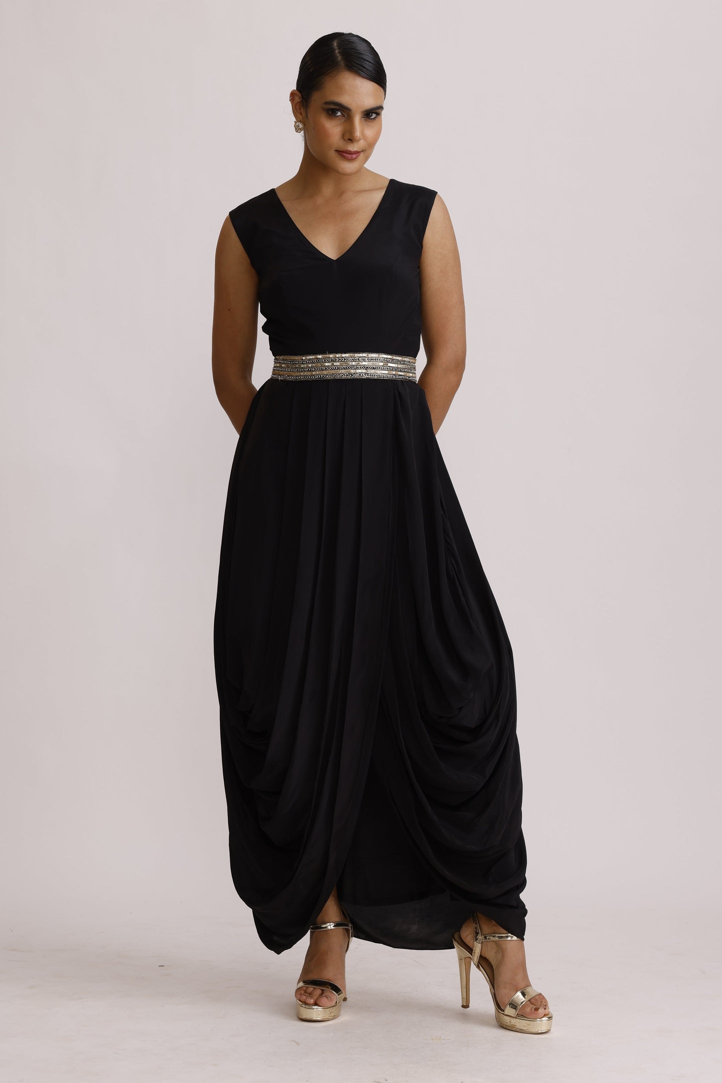 A woman modeling a sleeveless black floor-length gown with a silver beaded waistband, photographed against a plain light background.