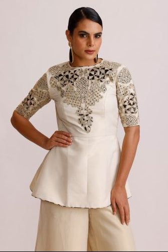 Woman wearing a white dress with intricate lace detailing on a plain background