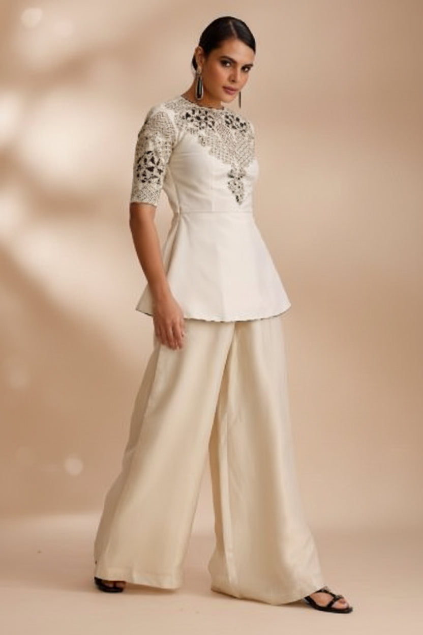 Woman wearing a cream-colored dress with intricate detailing on a white background