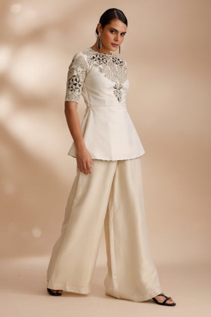 Woman wearing a cream-colored dress with intricate detailing on a white background