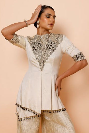 Woman wearing a traditional white dress with gold embroidery on a beige background