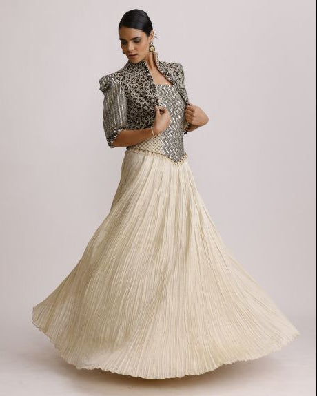 Woman wearing a patterned top and beige pleated skirt on a light background