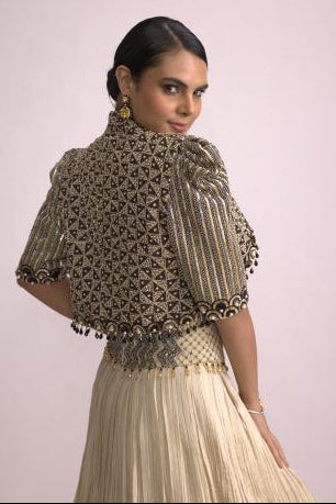Woman wearing a traditional outfit with intricate patterns on a plain background