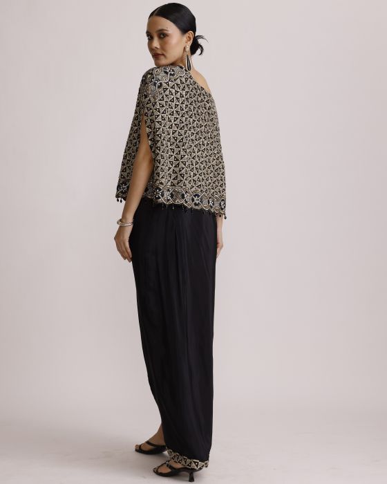 Woman wearing a patterned top and black pants on a plain background