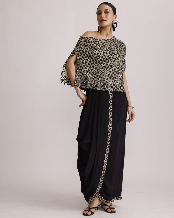 Woman wearing a patterned off-shoulder top and black pants with a belt against a light background