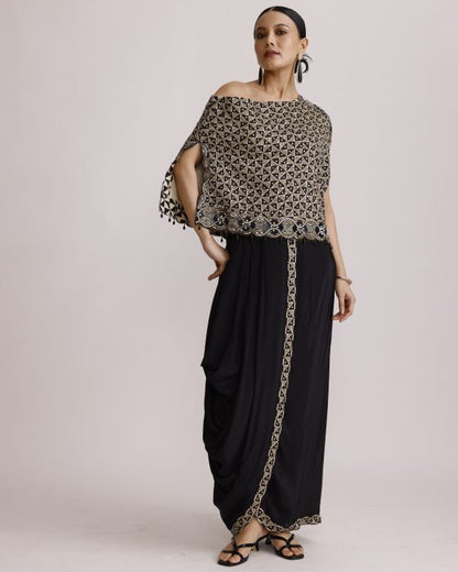 Woman wearing a patterned off-shoulder top and black pants with a belt against a light background
