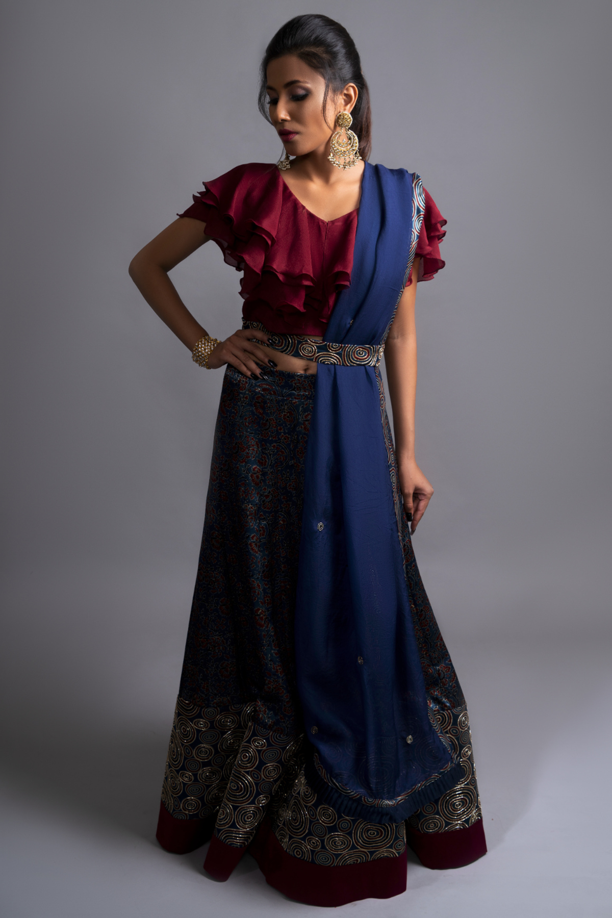 "Explore the allure of indigo Ajrakh print mashru silk lehenga with zardosi & Nakshi embroidery, paired with ruffled blouse & blue organza dupatta"