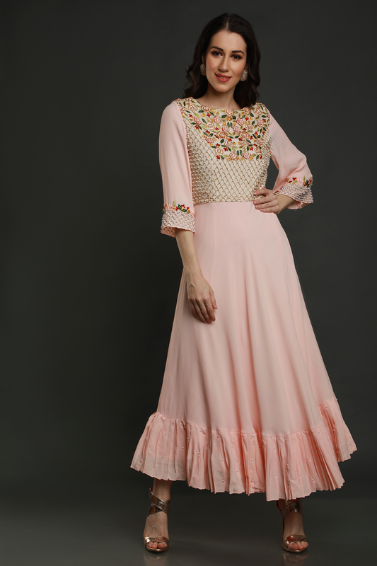 Step into elegance with a Light Peach crepe flared tunic dress. Hand-embroidered yoke, pleated panel, and exquisite detailing for a timeless look.